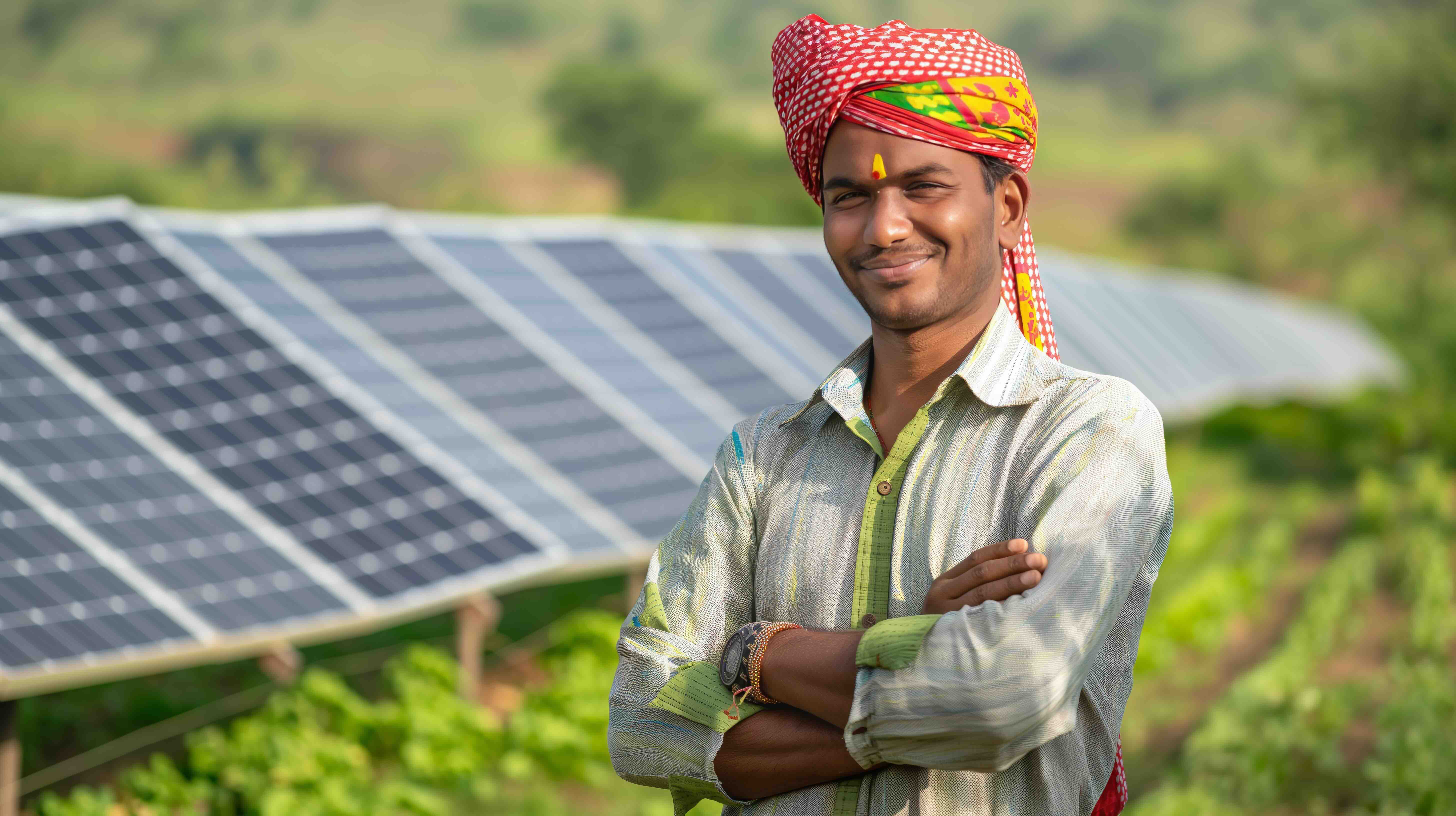 An Indian farmer in the foreground, on his farm, with solar panels in the background. The share of renewables in India's energy production is rising.
